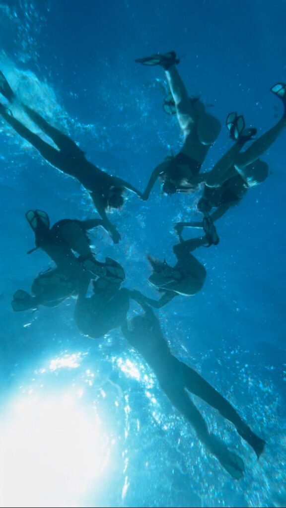 Group of snorkelers forming a circle underwater, captured from below against sunlight shining through the water during Snorkel Tour Playa de Palma