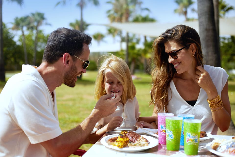 Hidropark Alcúdia, Activities & Sightseeing, Alcúdia, Mallorca, photo 1, Happy family enjoying a delicious meal together at Hidropark Alcúdia, surrounded by palm trees and sunny skies.