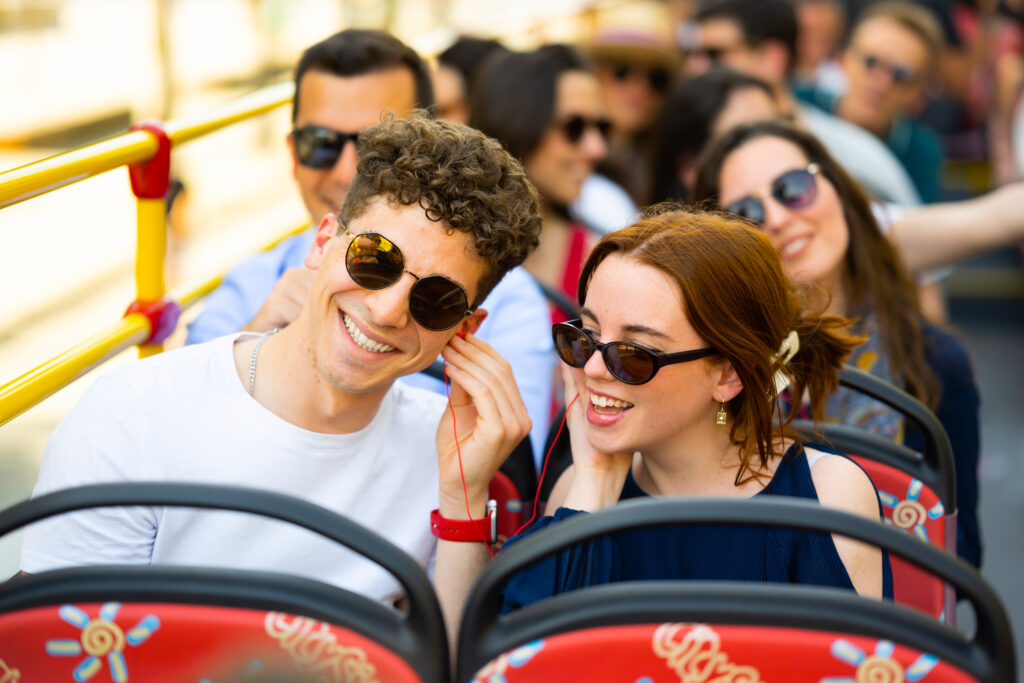 Smiling couple enjoying audio commentary on City Sightseeing Palma de Mallorca Hop-on Hop-off bus tour