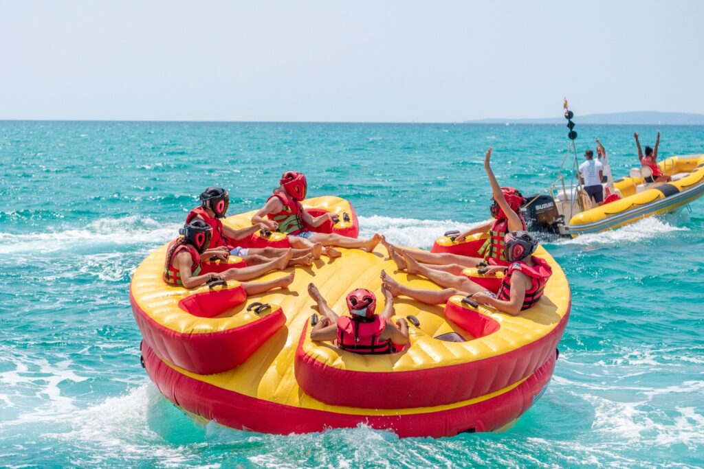 Group of people wearing life jackets and helmets enjoying an exciting ride on the Aqua Rocket Playa de Palma, gliding across the turquoise waves off the coast of Mallorca.