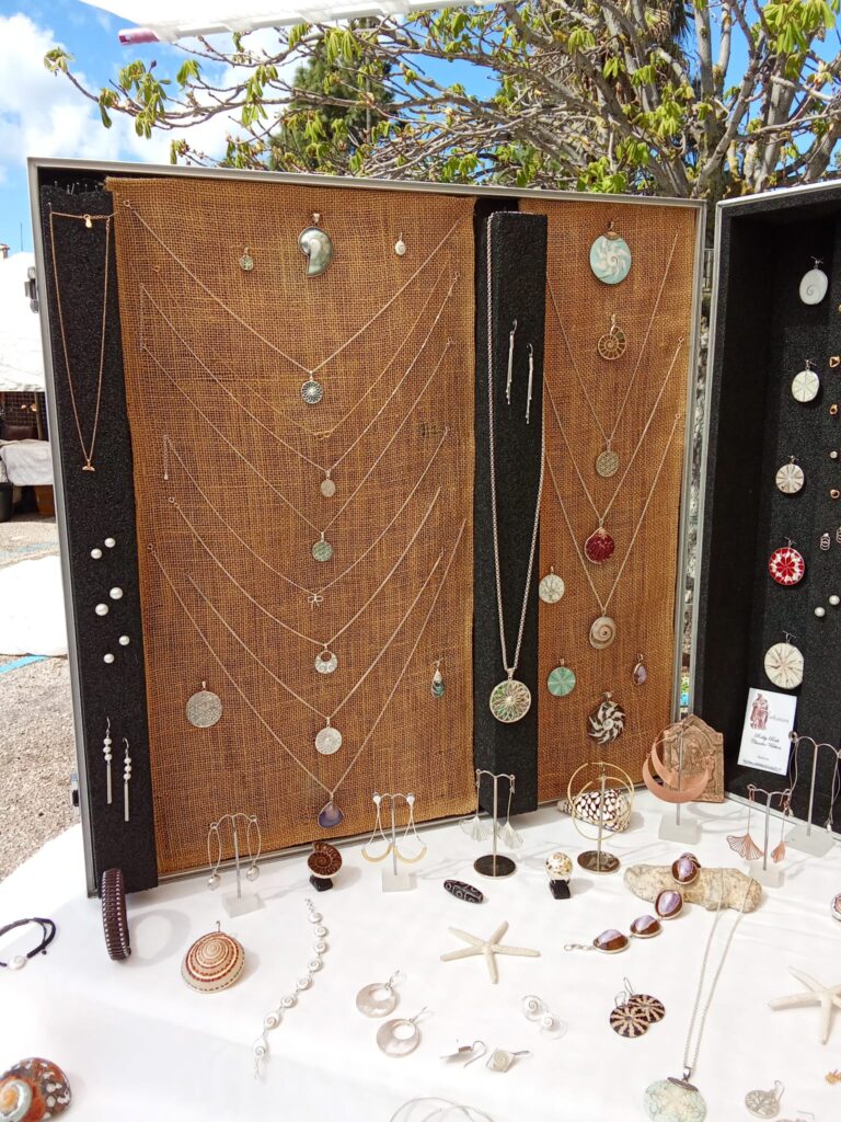 A jewelry stall at a Mallorca market displaying handcrafted necklaces, earrings, and pendants inspired by nature and marine elements.