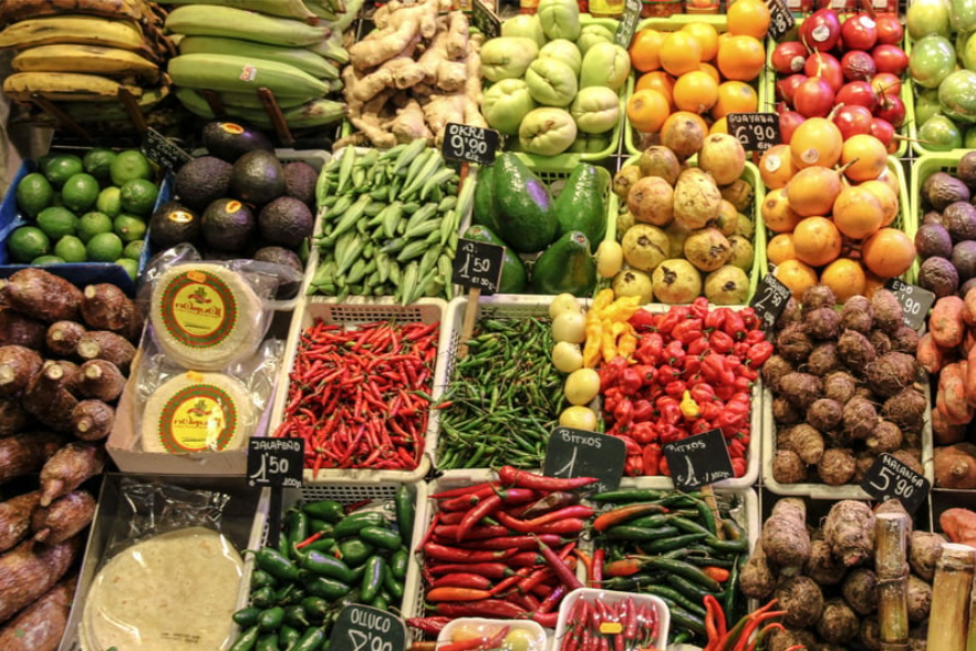Vibrant vegetable display at the weekly market Santa Maria del Camí in Mallorca, featuring peppers, avocados, beans, tomatoes, and other fresh local produce.