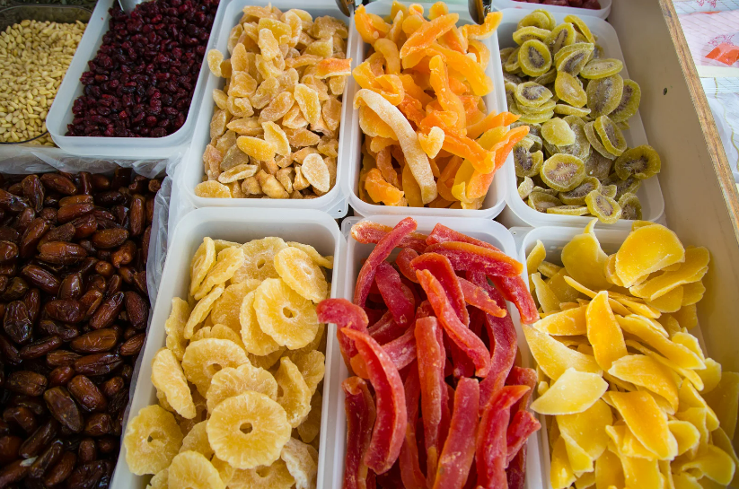Beautifully woven baskets filled with dried banana chips, coconut flakes, nuts, and mixed tropical fruits create an inviting display at the Pollença market, highlighting local and exotic delicacies.