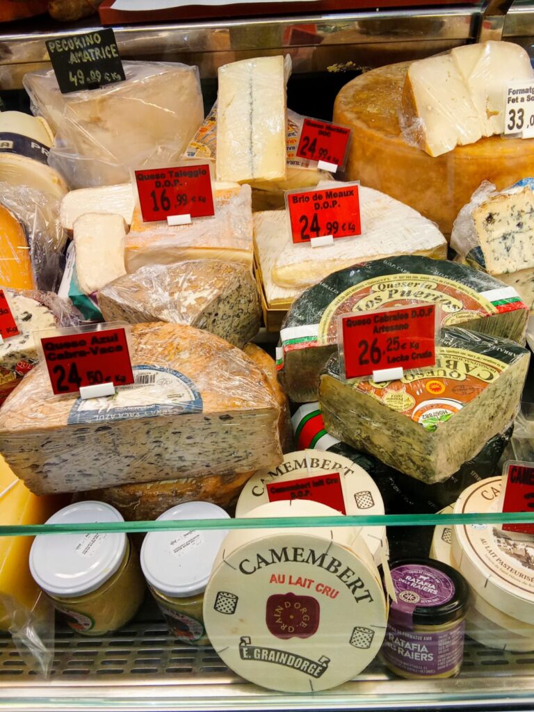 Selection of local cheeses displayed at a dairy counter inside Mercat Pere Garau.