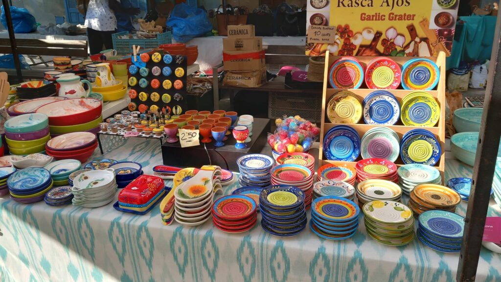 A ceramics stall at the market, featuring vibrant hand-painted plates, bowls, and garlic graters.