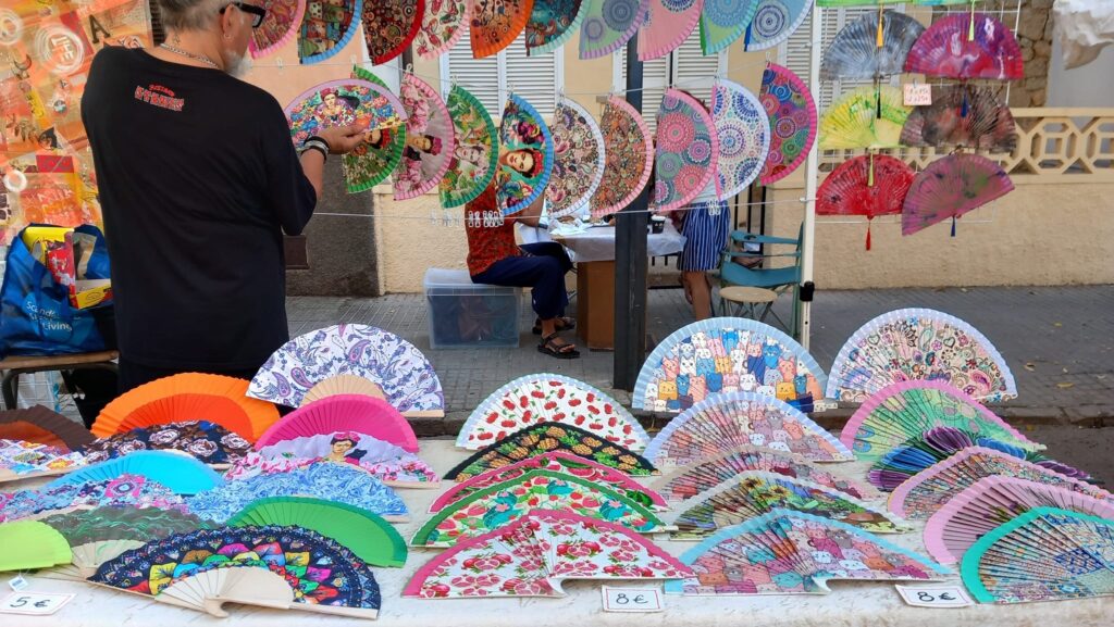 A colorful market stall selling hand-painted Spanish fans, with intricate designs and cultural motifs.