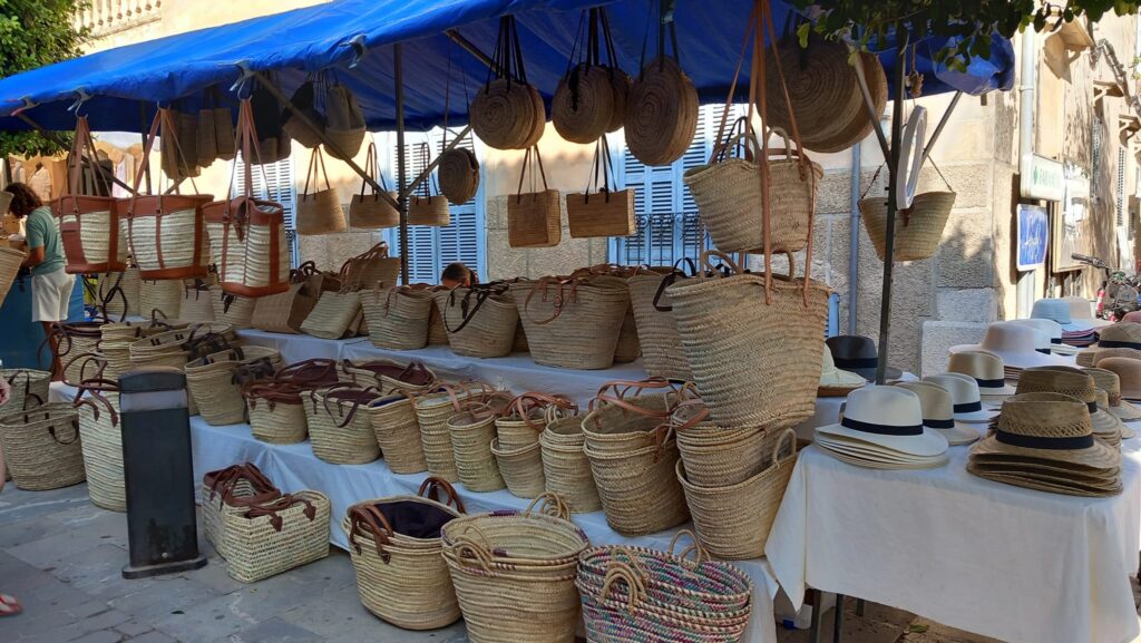 A market stand featuring traditional woven baskets, handbags, and straw hats, showcasing Mallorca's artisan craftsmanship.