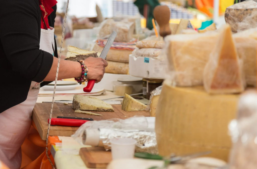 Local vendor slicing artisanal Mallorcan cheese at weekly market Calvià – showcasing traditional island flavors and handmade dairy specialties.