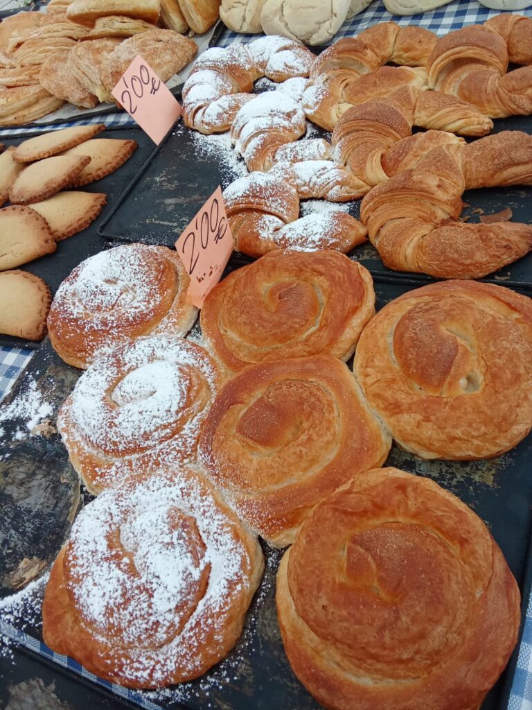 Traditional Mallorcan pastries like ensaimadas, croissants, and empanadas freshly baked and sold at the Weekly Market Paguera.