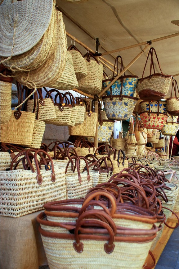 Lively street at the weekly market in Sant Elm Mallorca with souvenir stalls, hats, and Mediterranean atmosphere.