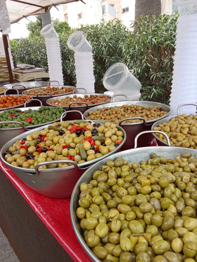 Large bowls filled with different varieties of olives, including green, black, and stuffed olives, displayed at the Weekly Market in Santa Ponsa, Mallorca.