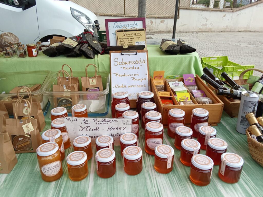A market stall at the Weekly Market in Santa Ponsa, Mallorca, offering local honey, handmade sobrasada, herbal teas, and artisanal products.