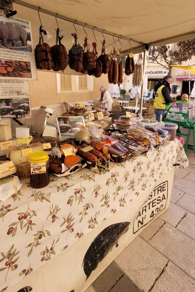 A stall at the Weekly Market Santanyí, selling artisanal cured meats, cheeses, and honey, showcasing authentic Mallorcan flavors.